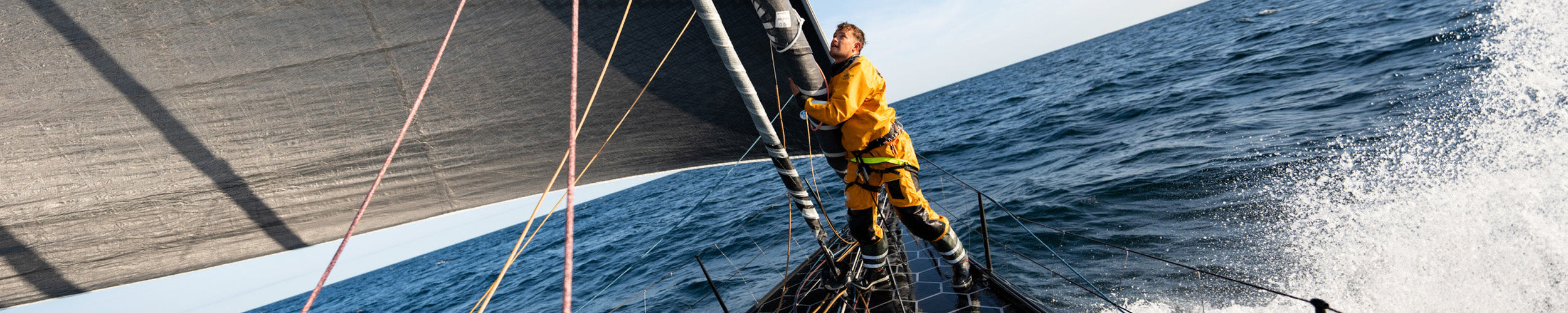 Wide image of a member from Team Guyot in action while at sea during the sixth leg of the Ocean Race 2023.